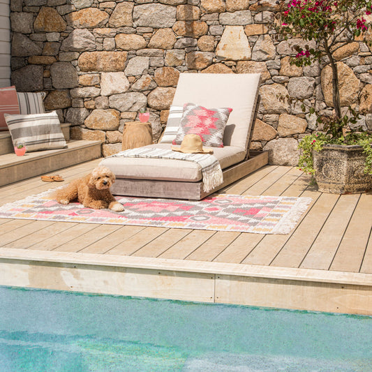 Pet-friendly washable outdoor rug in pink diamond pattern on timber pool deck